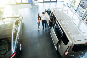 Young handsome salesman working with client in car dealership