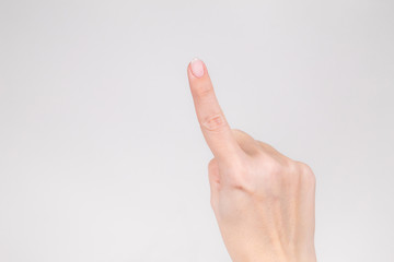 Closeup view of beautiful female hand raising up one index finger. Horizontal color photography.