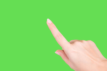 Closeup view of beautiful female hand with pastel nude look manicure isolated on green bright background. Woman raising one index finger up. Horizontal color photography.
