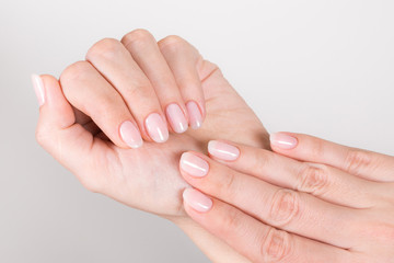 Closeup top view of beautiful natural pastel manicure at white hands of woman. Horizontal color...