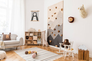 Stylish scandinavian interior design of childroom with gray sofa, modern climbing wall for kids,...
