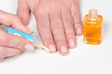 Closeup view of white woman applying cuticle oil to skin after manicure. Horizontal color photography.