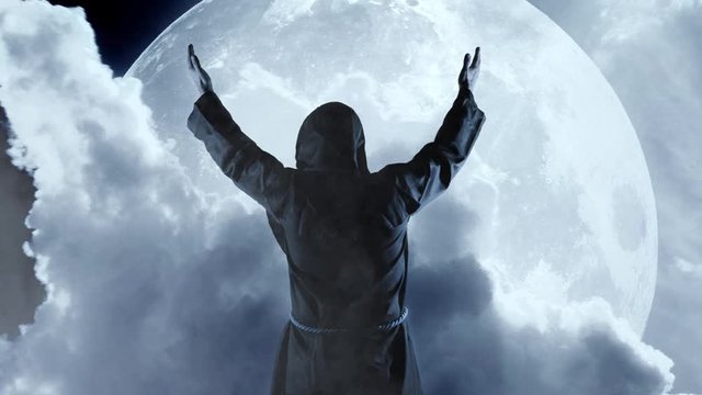 Silhouette of a Monk in a cassock against a full moon