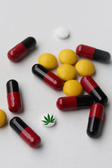 colored drugs, white pills, capsules with marijuana leaf icon on a white background, medical cannabis concept, top view, close-up, copy space