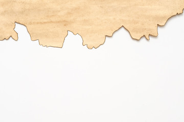 Cropped shot of old stained beige paper with burnt edge on white background. Vintage texture abstract design. Copy space.