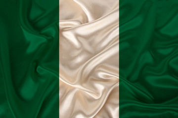 photo of the national flag of Nigeria on a luxurious texture of satin, silk with waves, folds and highlights, closeup, copy space, travel concept, economy and state policy, illustration