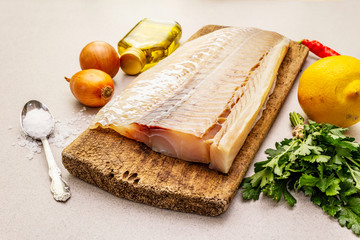 Raw cod loin fillet with vegetables, spice, olive oil and salt.
