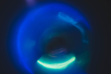 Blur neon blue glow. Colored lens flare. Dark abstract background. Defocused circle light.