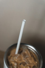 white plastic straw and cup of iced coffee stainless steel cup