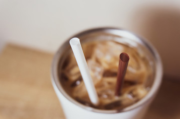 Brown and white straw in iced coffee. Stainless steel cup