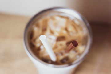 Brown and white straw in iced coffee. Stainless steel cup