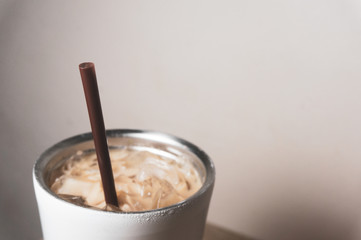 brown plastic straw in a cup of iced coffee stainless steel cup