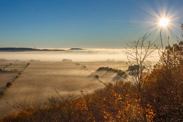 View of an agricultural landscape with the sun and fog