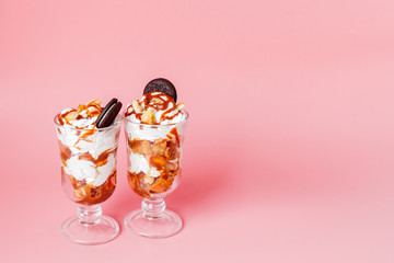 Sweet dessert in glass with biscuit and whipped cream on pink bsckground, selective focus and blank space