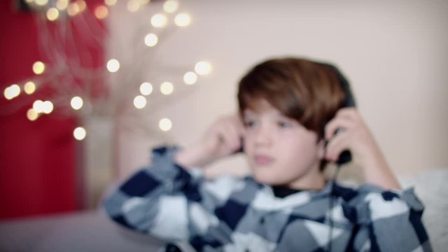 4k Relaxed Child Listening to Music in Headphones on Couch