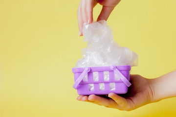 polythene bags in hand in shopping basket on yellow background