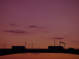 Silhouette of a bridge over a river at sunset, cityscape