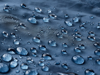 Rain water droplets on blue fiber waterproof fabric. Blue background. - obrazy, fototapety, plakaty