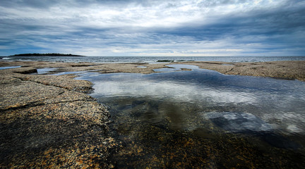 Dramatic sky Reflected in beautiful calm water in Gulf of Bothnia. Rotsidan, High Coast in northern Sweden.