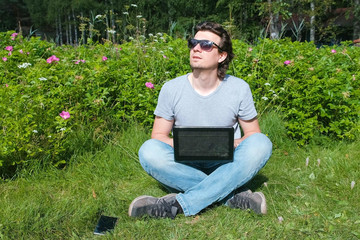 Mam is working typing on laptop sitting in Park in summer