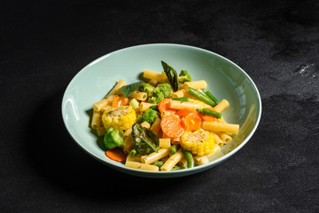 Delicious fresh warm paste sprinkled with cheese parmesan with broccoli, corn, carrots and other vegetables. Vegetarian food