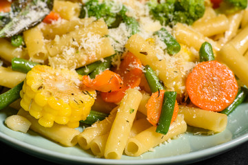 Delicious fresh warm paste sprinkled with cheese parmesan with broccoli, corn, carrots and other vegetables. Vegetarian food