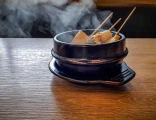 Korean fish cake and vegetable hot soup in black ceramic bowl on wood table