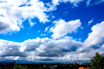 Fototapeta premium Blue sky with white clouds, town in the distance