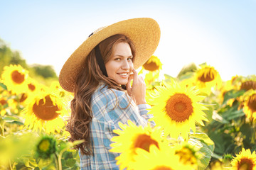 Beautiful young woman in sunflower field on summer day