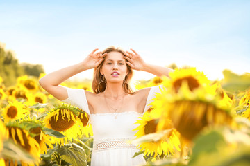 Fototapeta na wymiar Beautiful young woman in sunflower field on summer day