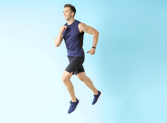Fototapeta premium Running sporty man on color background