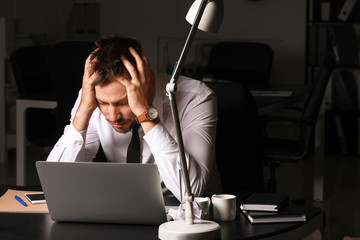 Stressed man at workplace late in evening
