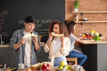 Happy couple eating tasty melon in kitchen