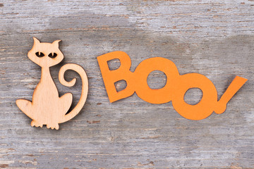 Halloween holiday decorations on wooden background. Wooden silhouette of cat and word boo on wooden surface.