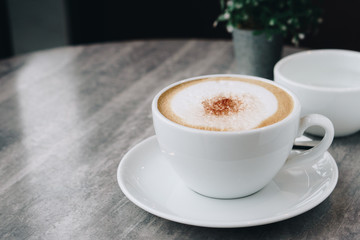 Hot coffee, white cups, plate, spoon all  placed on the black - brown circle wooden table.