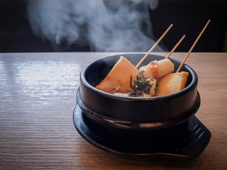 Korean fish cake and vegetable hot soup in black ceramic bowl on wood table