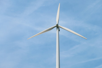rotating blades of a windmill propeller on blue sky background. Wind power generation. Pure green energy.