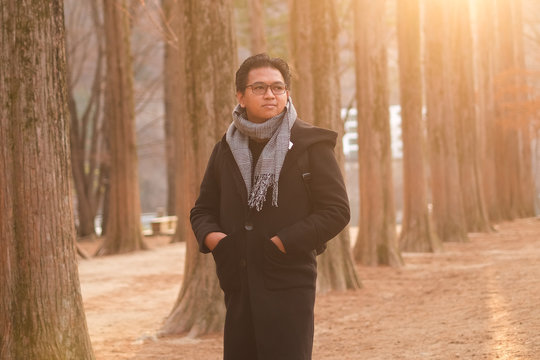 Asian male with winter coat, scarf or Muffler scarf; shot three quarter during holiday on forest.
