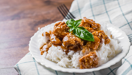 Chicken Breast with sauce and Rice in white plate on a wooden table background