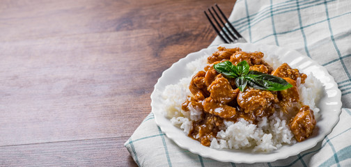Chicken Breast with sauce and Rice in white plate on a wooden table background