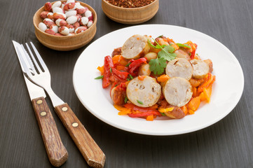 Stewed beans with vegetables and sausages. on black background.