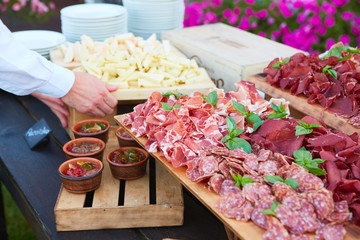Plate and board with assortment of delicious deli meats on table
