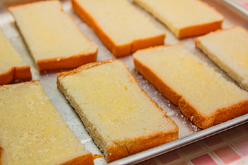 Breakfast preparation buttered bread and sugar.