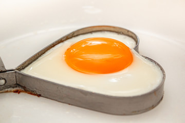 Fried eggs heart shape homemade meal on a frying pan.