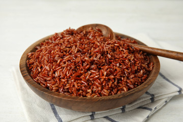 Wooden bowl with delicious cooked brown rice on white table
