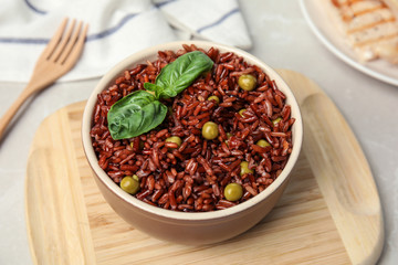 Bowl with delicious cooked brown rice on table