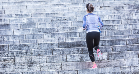 Young woman doing sports and running up the stairs