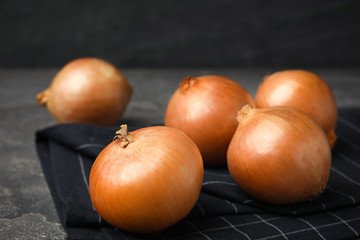 Black fabric with ripe onions on grey table