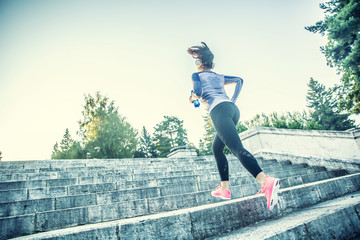 Young woman doing sports and running up the stairs