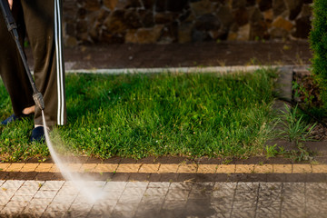 Close up photo of a man hands, cleans a tile of grass in his yard. High pressure cleaning